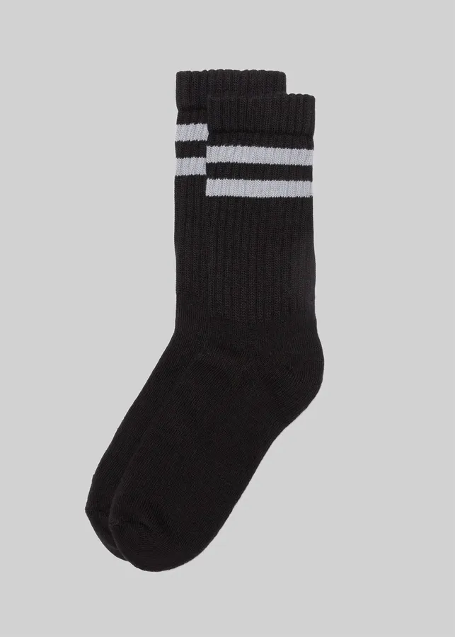 A pair of black ribbed crew socks with double white stripes near the top, shown crossed against a light grey background.