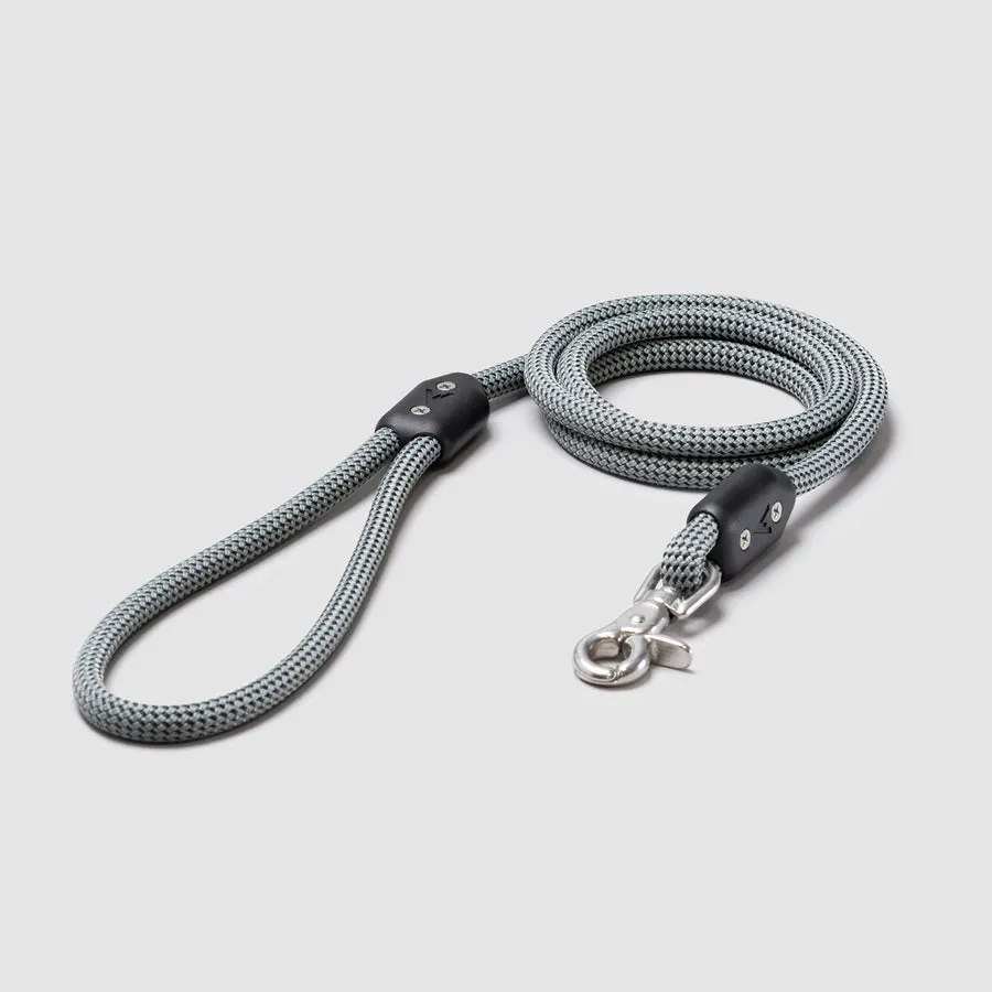 A coiled gray climbing-rope-style dog leash with a black handle loop and a silver clasp, on a light gray background.