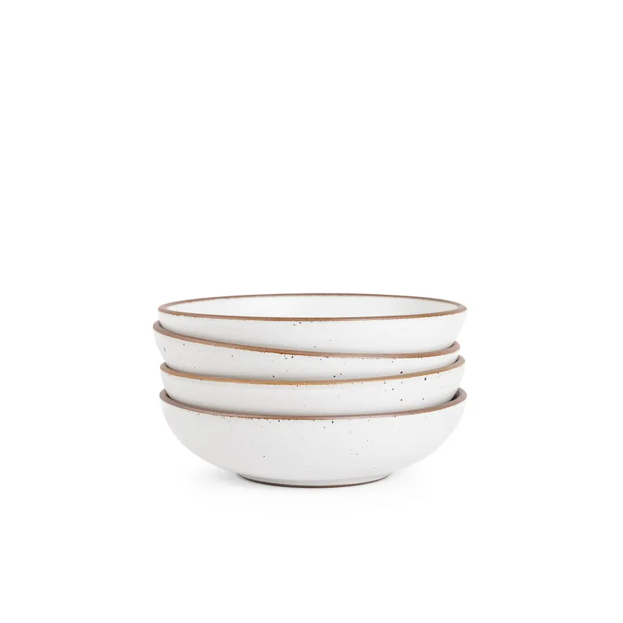 A stack of four white speckled stoneware bowls with tan unglazed rims, shot on white.