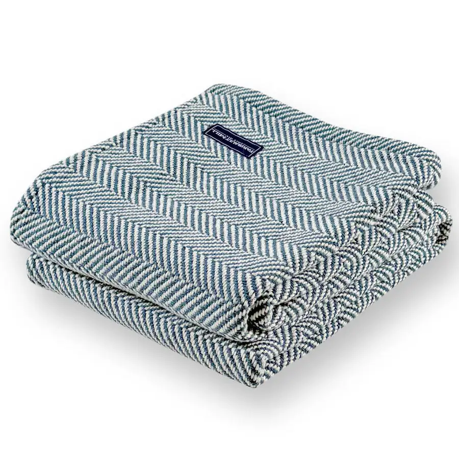 A blue-and-white herringbone cotton throw folded into a neat square with a Faribault Mill label, on a white background.