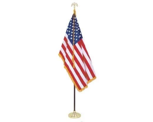 An American flag with gold fringe mounted on an indoor display pole with a gold eagle finial and round gold base, against a white background.