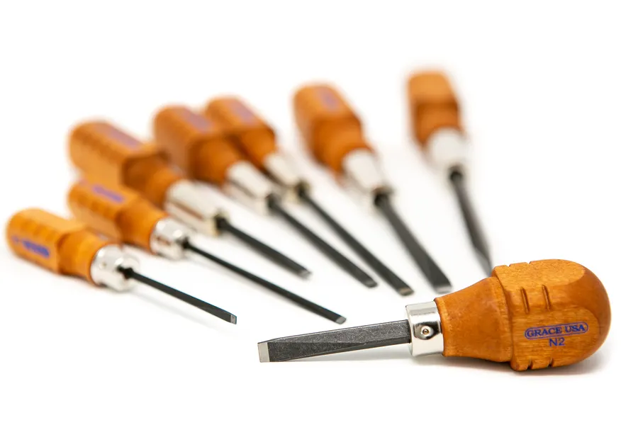 A fan of Grace USA gunsmithing screwdrivers laid out on a white background, shot at a low angle with one wood-handled driver stamped N2 in sharp focus in the foreground and the rest fading into soft focus behind it.