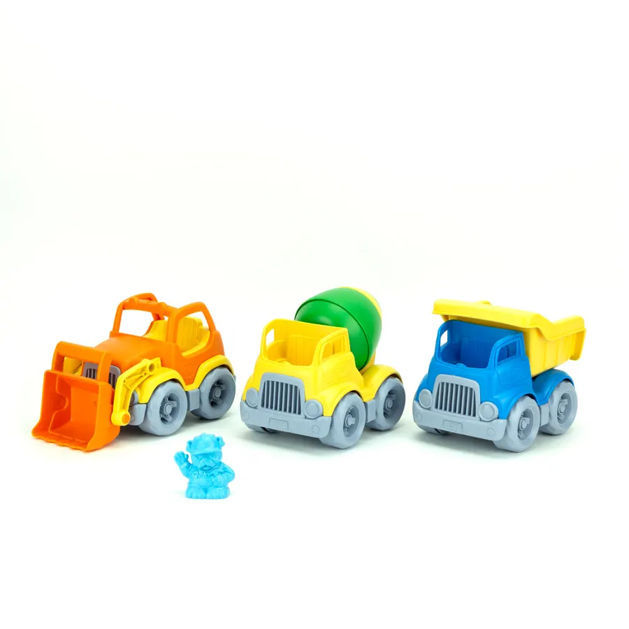 Three Green Toys construction vehicles -- an orange front loader, a yellow-and-green cement mixer, and a blue-and-yellow dump truck -- with a small blue toy figure, arranged on a white background.