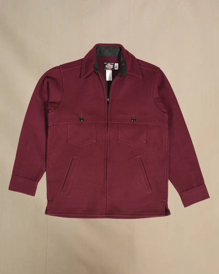 A burgundy wool jac shirt jacket with a zip front, two snap-flap chest pockets, and slash hand pockets, laid flat against a tan backdrop.