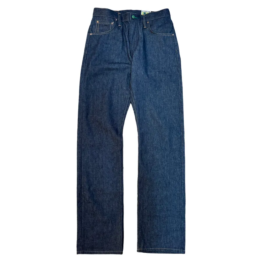 A pair of dark indigo selvedge denim jeans laid flat against a white background, showing the straight leg cut and tan leather waistband patch.
