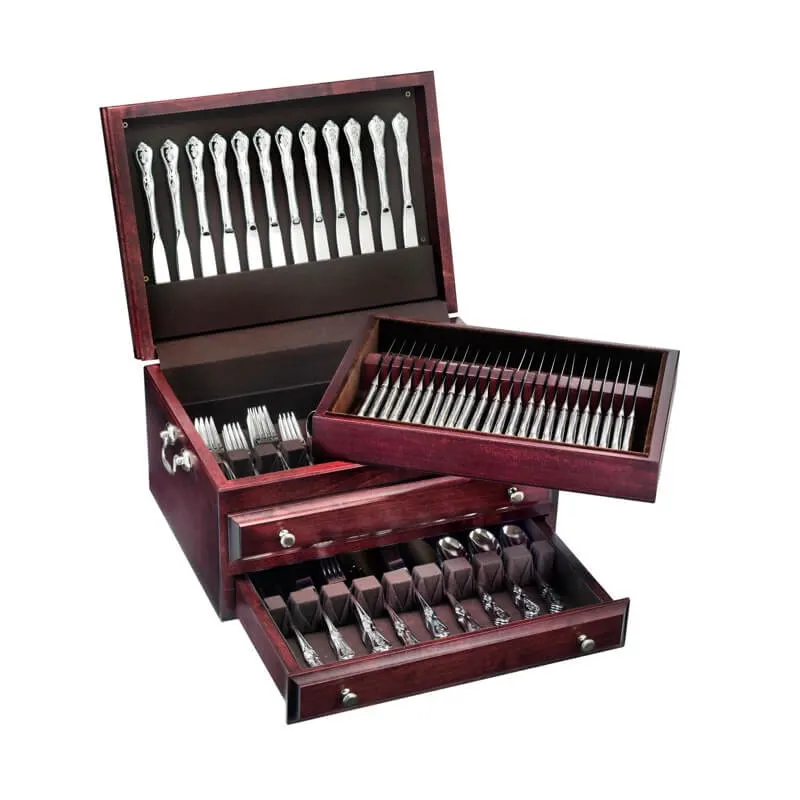 An open mahogany flatware chest with three fitted drawers, each lined in felt and holding rows of polished silver-pattern forks, knives, and spoons.