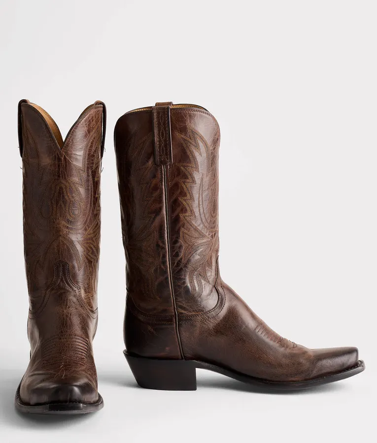 A pair of chocolate brown textured goat-leather cowboy boots with western stitching, shot on a white background.