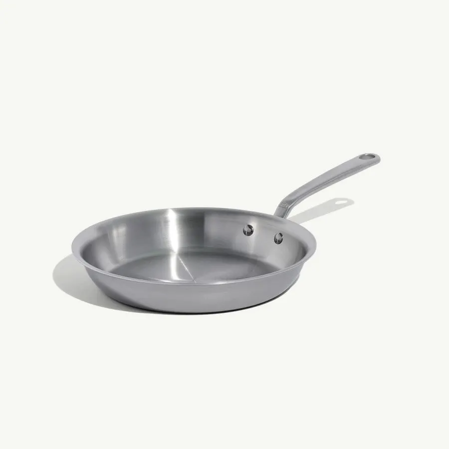 A stainless steel frying pan with a long brushed handle, shown at an angle against a plain light gray background.