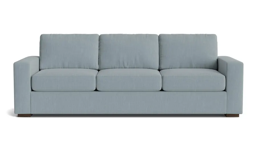 A three-seat sofa with pale blue-grey woven upholstery, boxy track arms, and dark wood block feet, shown straight-on against a white background.