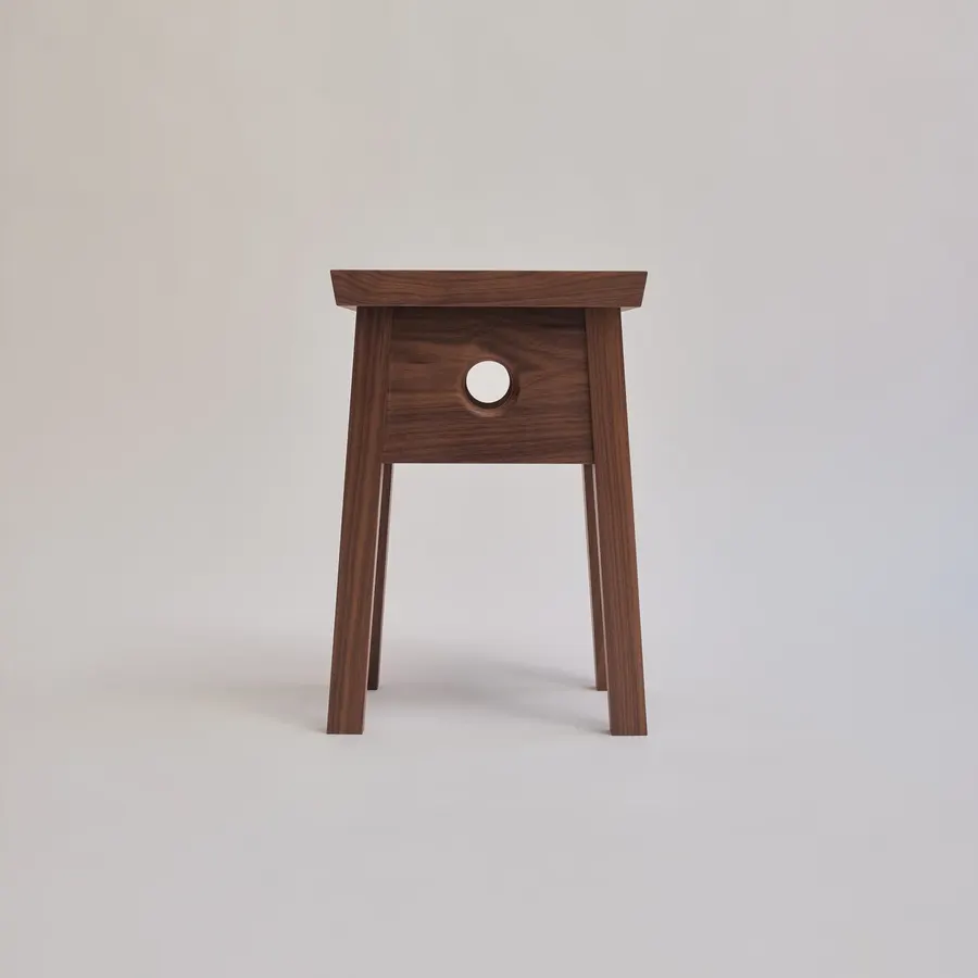 A four-legged wooden stool with a square drawer-like apron featuring a round cutout, shown against a plain light grey background.