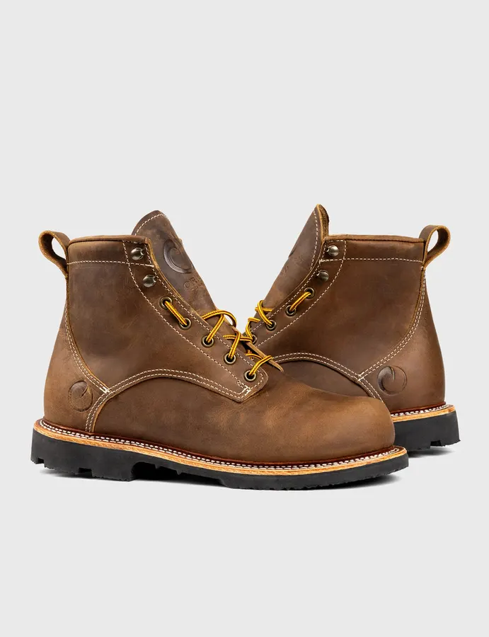 A pair of brown leather 6-inch lace-up work boots with round toes, yellow laces, and black lugged soles, photographed at an angle against a plain light-grey background.