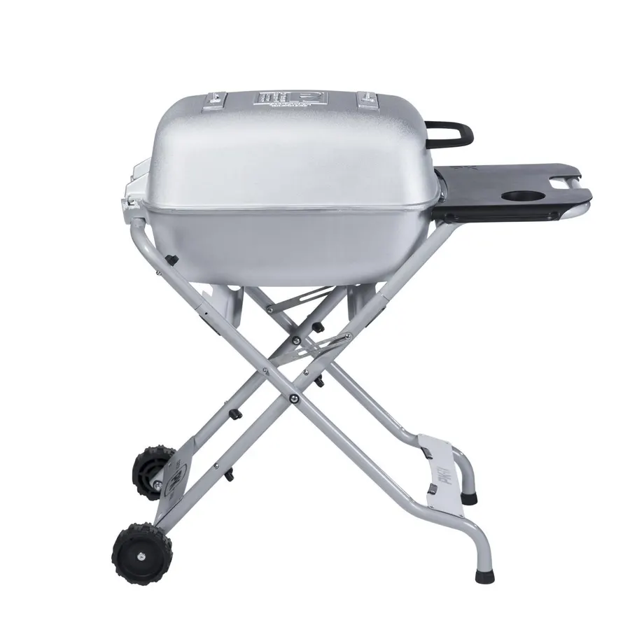 A silver cast-aluminum portable charcoal grill with its hood closed, folded X-frame legs, a side shelf, and two small wheels, photographed in profile against a white background.