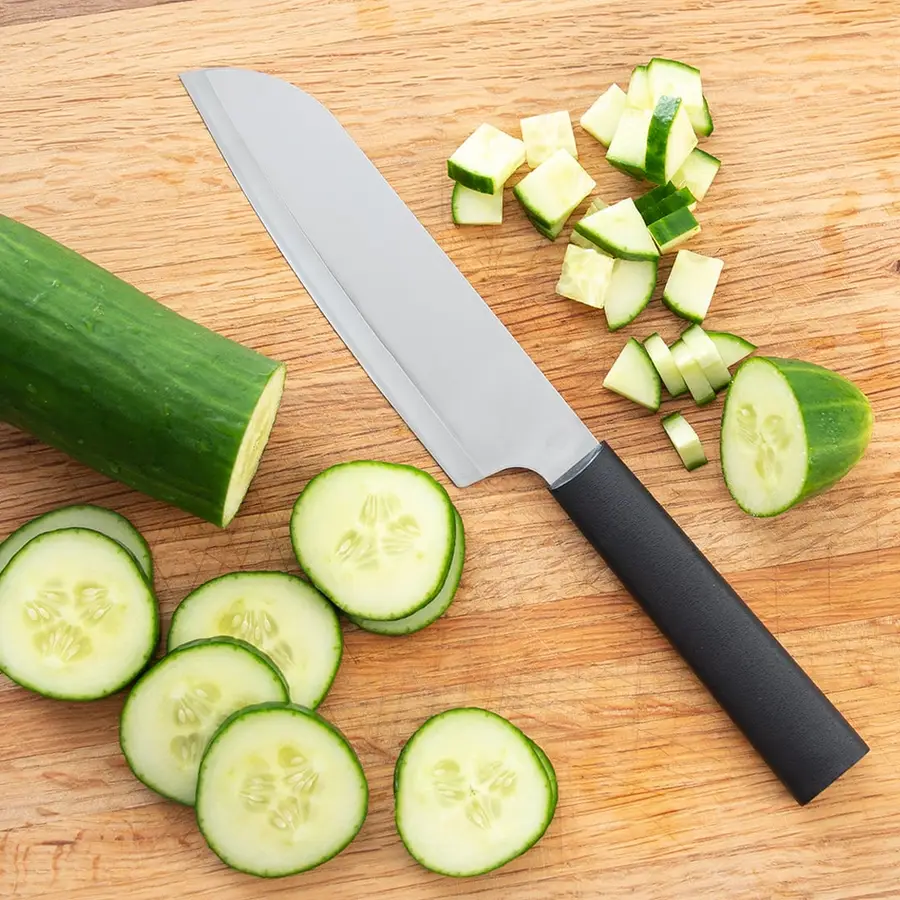 A stainless steel Rada chef's knife with a black handle, resting beside chopped and sliced cucumber on a wooden cutting board.