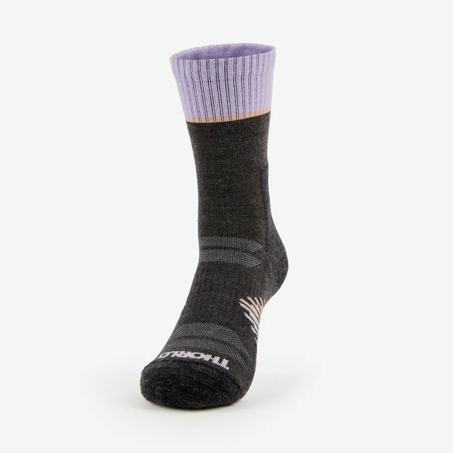 A charcoal grey wool hiking crew sock with a lavender cuff and peach accent stripe, shown on an invisible foot form against a white background, with the THORLO wordmark knit into the toe.