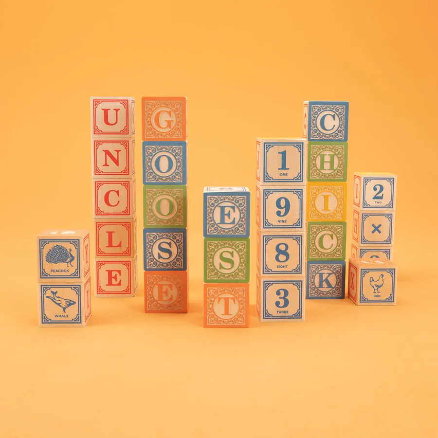 Stacks of cream-colored wooden alphabet blocks with ornate printed letters, numbers and animal illustrations spelling UNCLE GOOSE, CHICK, and 1983, on an orange background.