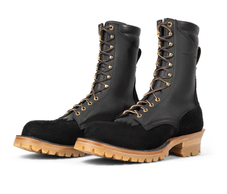 A pair of tall black leather logger boots with black suede toe caps, gold eyelets, and honey-colored lug soles, shown as a matched pair against a white background.