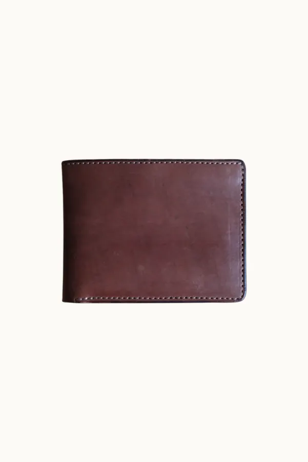 A brown leather bifold wallet with visible edge stitching, shot flat on a cream background.